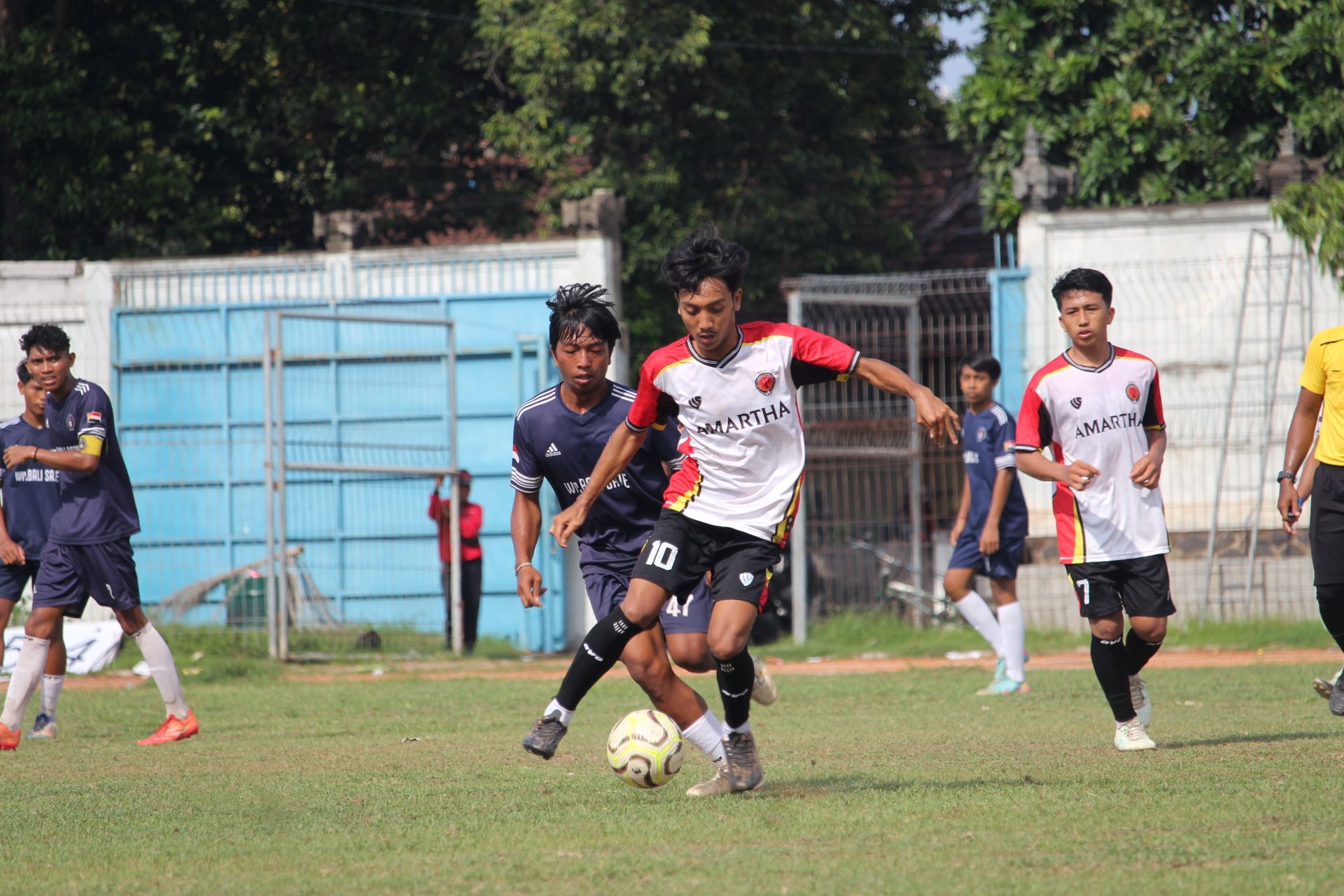 KETAT: Pemain Amartha FC Patas (putih) mengawal bola dari kejaran pemain Satria Muda Pengulon (biru) dalam pertandingan pada Kamis (11/12/2025).