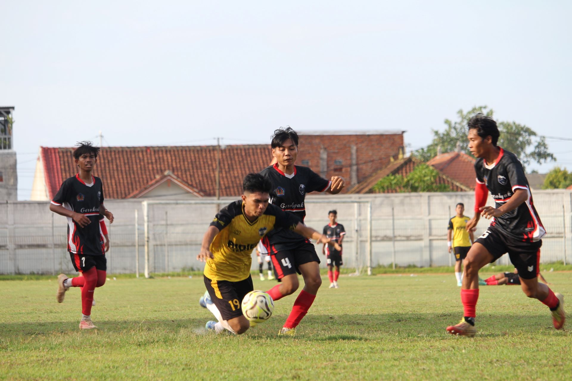 TERJATUH: Pemain Gondol FC Penyabangan (kuning) terjatuh saat berebut bola dengan pemain Persega Gerokgak (hitam) dalam pertandingan  Liga 3 PSSI Buleleng, Jumat (12/12/2025).