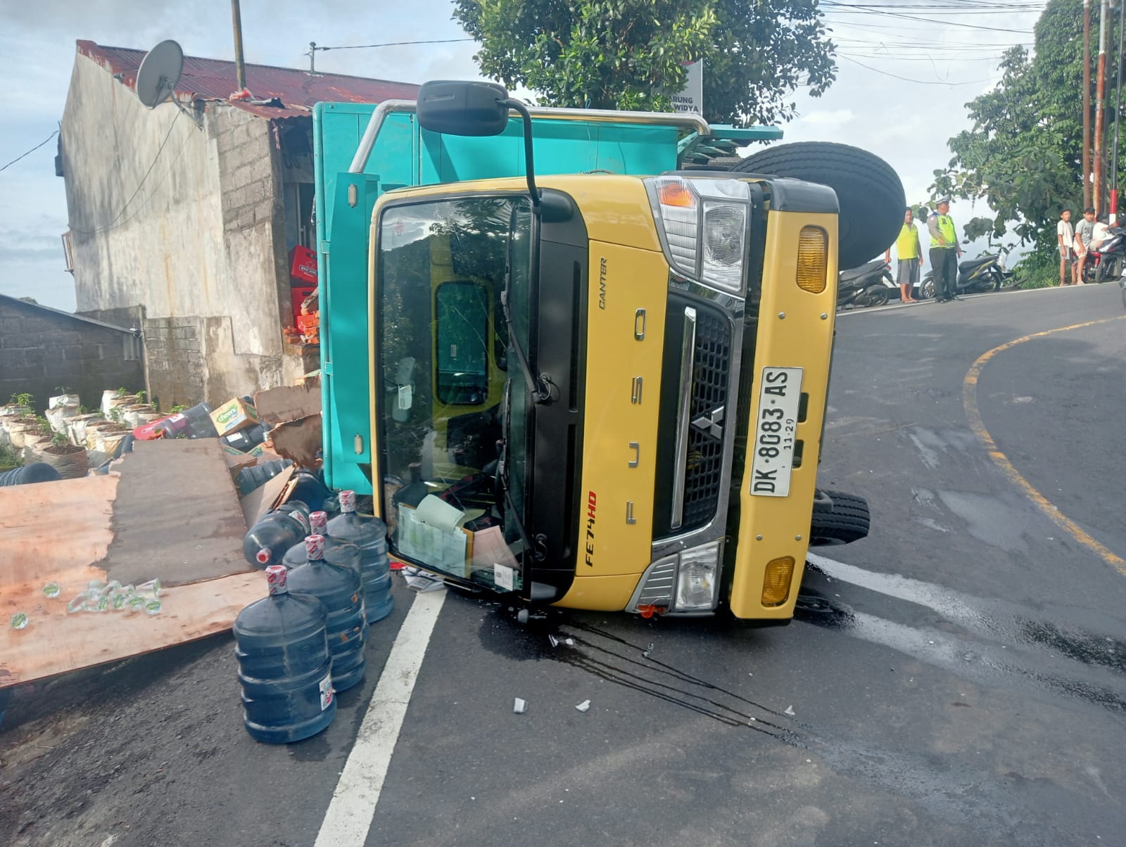 TERGULING: Truk bermuatan air mineral terguling di Jalan Raya Singaraja-Denpasar, Desa Gitgit.