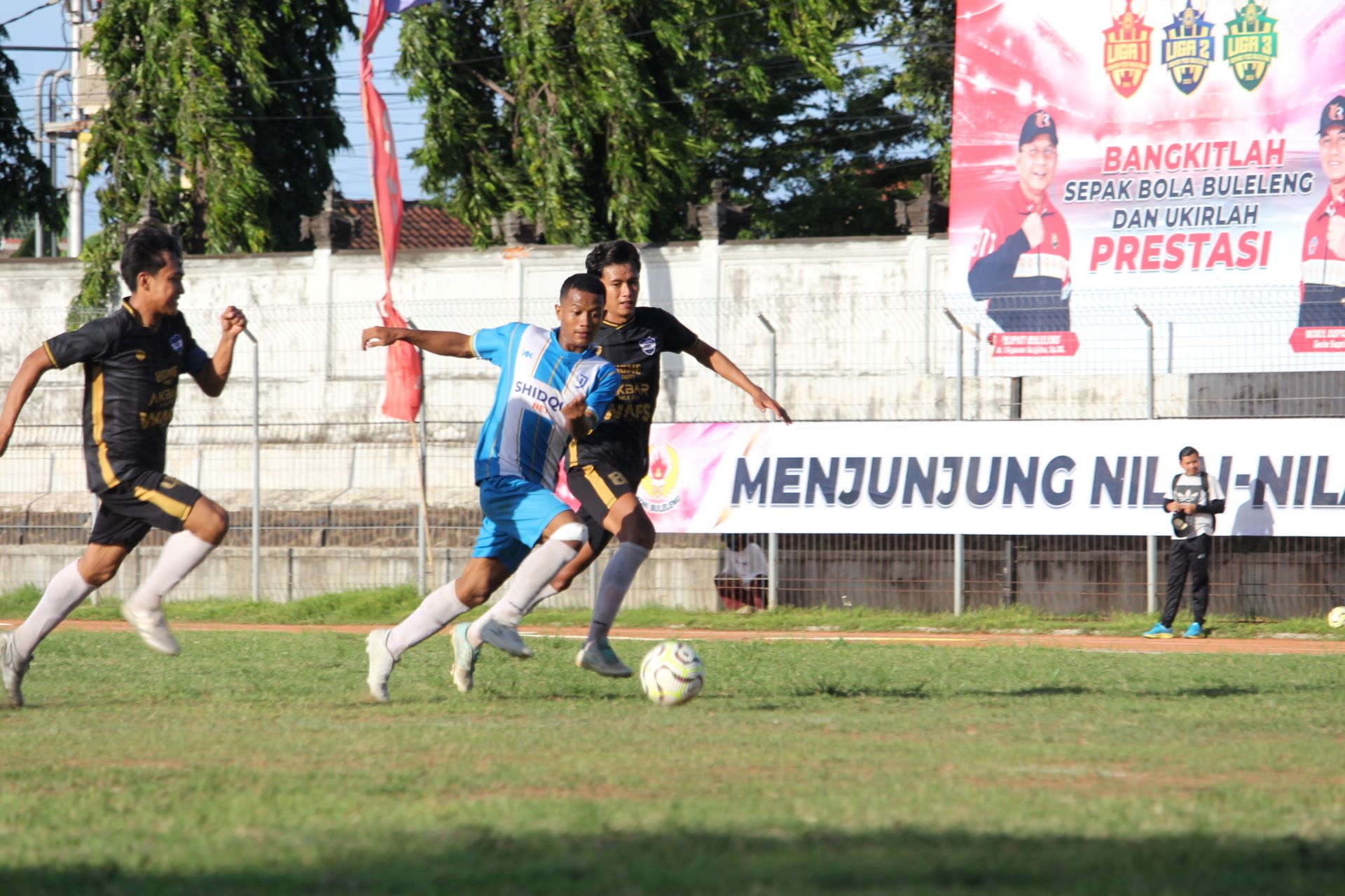 REBUT TIKET FINAL: Pemain Intan Jaya FC Celukan Bawang (biru-putih) berusaha mempertahankan bola dari pemain Gondol FC Penyabangan (hitam) dalam pertandingan Selasa (23/12/2025).