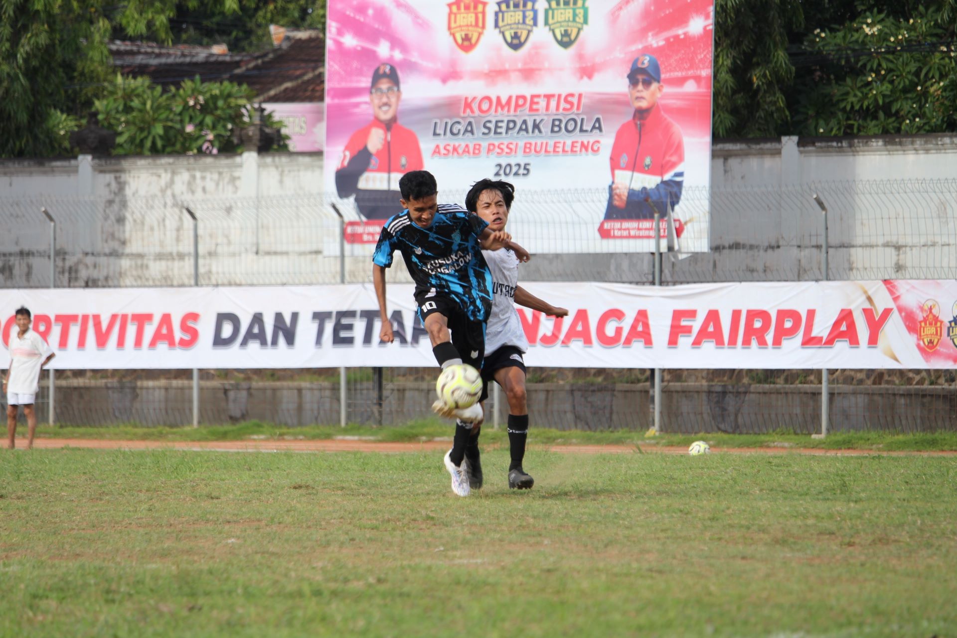 CETAK GOL: Gelandang Tunas Harapan Pengastulan, Rangga (biru) melepas tendangan saat dikawal pemain PERS Sangsit (putih), dalam pertandingan di Stadion Mayor Metra, Rabu (24/12/2025).