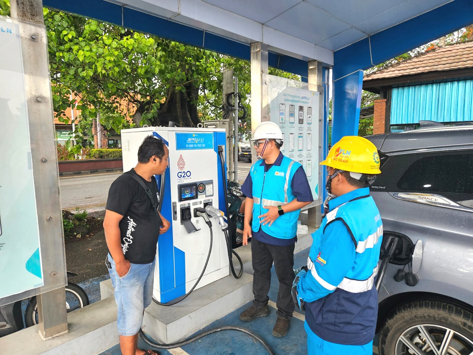 LAYANI WISATAWAN: Petugas PLN melayani wisatawan domestik yang melakukan pengisian SPKLU di Anjungan Betutu Gilimanuk.
