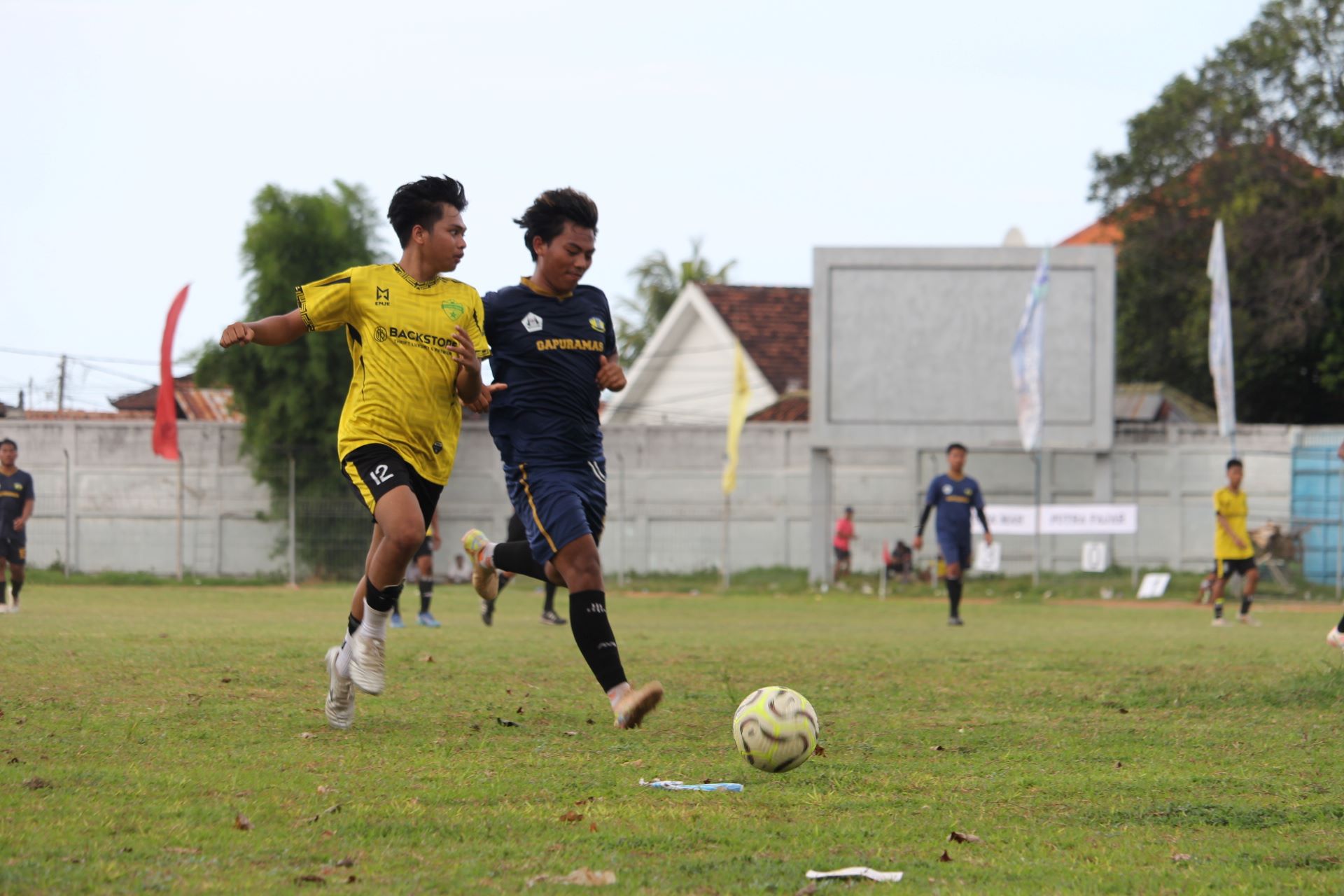KEJAR BOLA: Pemain Gapura Mas Sanggalangit (biru) mengejar bola di bawah bayangan pemain Putra Fajar Patas (kuning).