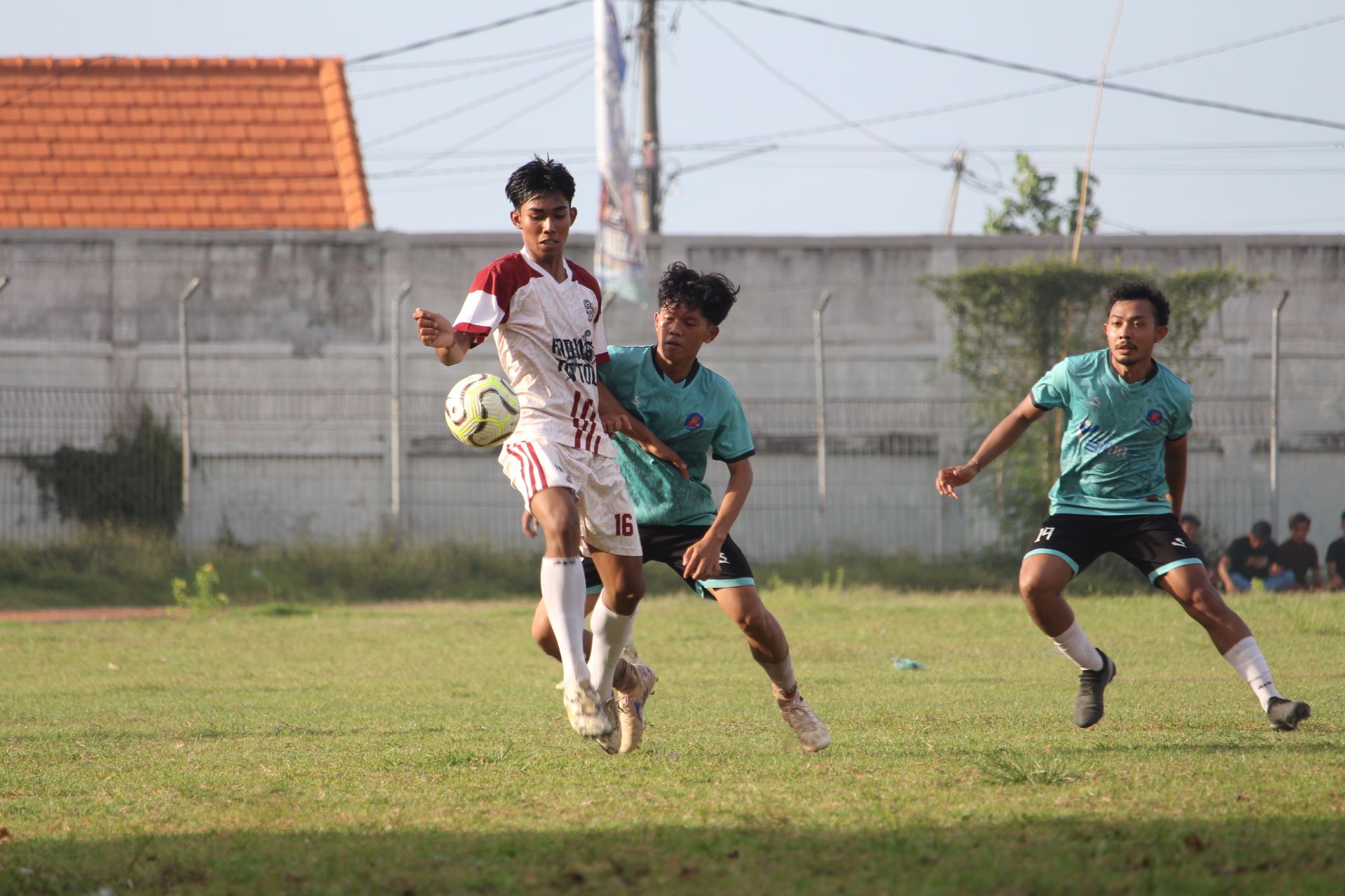 MENUJU LIGA 1: Pemain Teja Harum Tejakula (putih) mengamankan bola dari pemain Singa Anturan (biru) dalam pertandingan di Stadion Mayor Metra Singaraja, Sabtu (27/12/2025).
