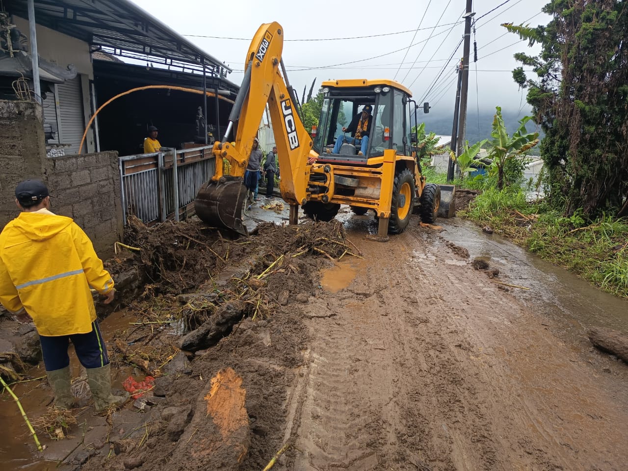 BERSIHKAN JALAN: Alat berat tampak membersihkan lumpur yang menutupi akses jalan warga di Desa Pancasari.