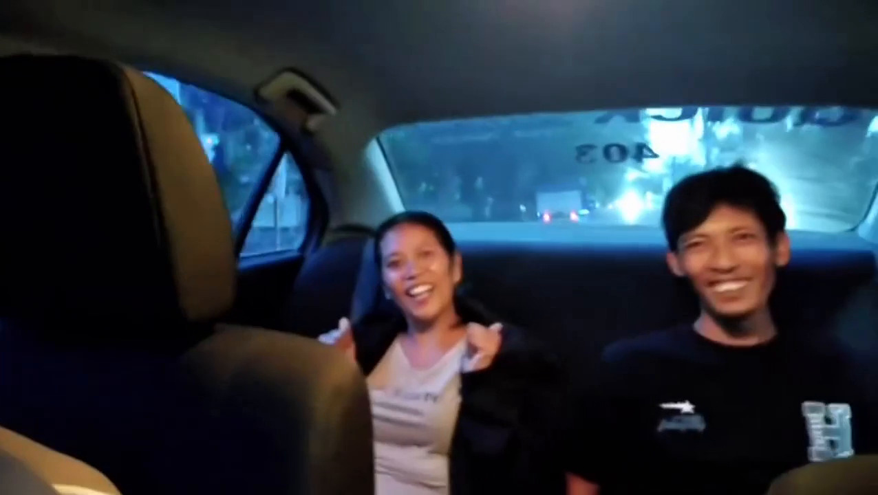 BAHAGIA: Putu Gede Budiasa (kanan) bersama istrinya tersenyum bahagia saat mendapat kesempatan naik mobil patroli polisi. Sang istri yang tengah hamil muda, ngidam naik mobil polisi.