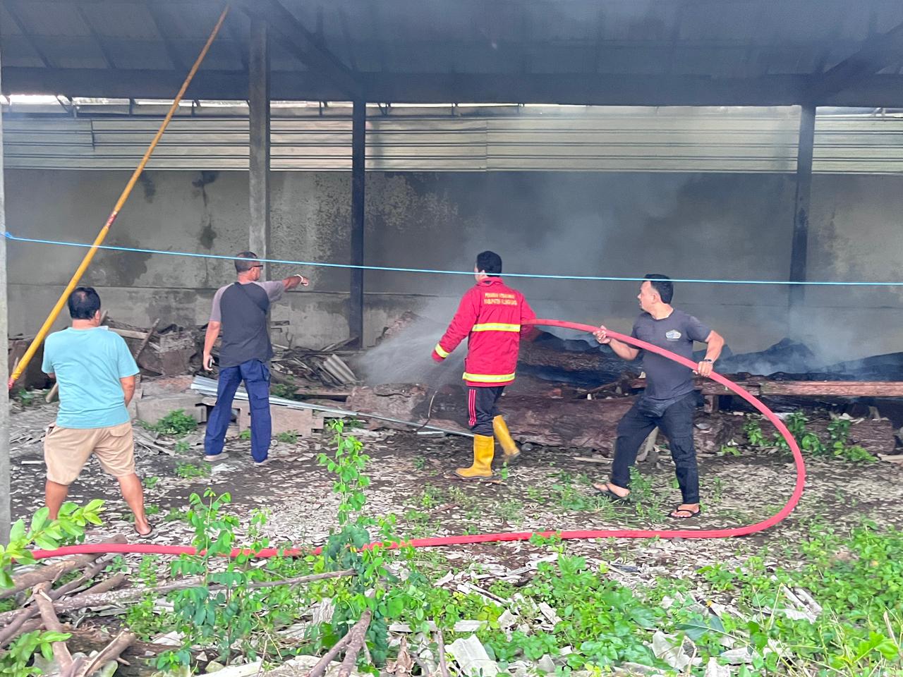 KEBAKARAN: Petugas pemadam kebakaran berusaha memadamkan api yang membakar tumpukan kayu gelondongan di gudang.