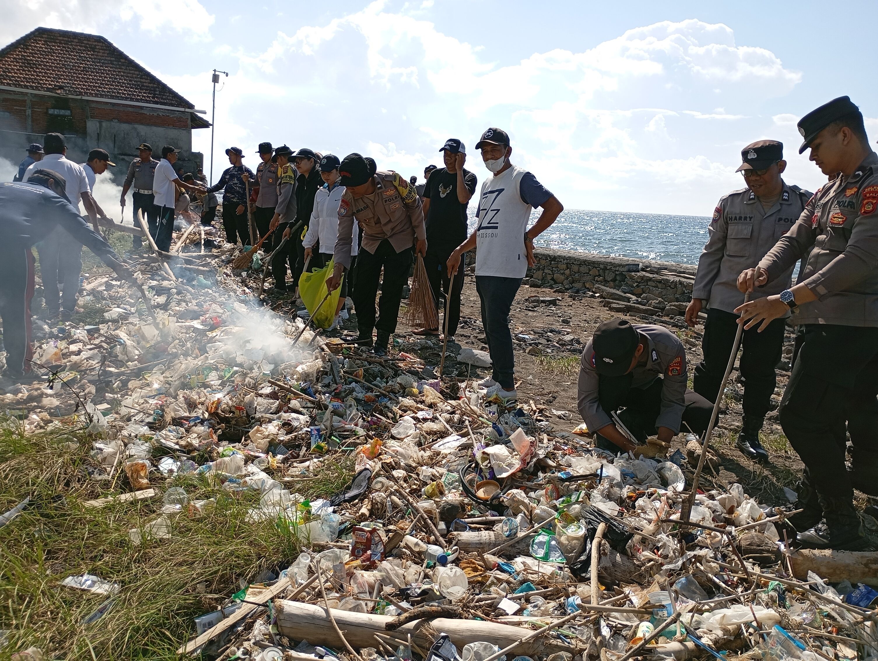 BERSIHKAN SAMPAH: Aparat kepolisian Polres Buleleng membersihkan sampah di Pantai Happy, Desa Tukadmungga.