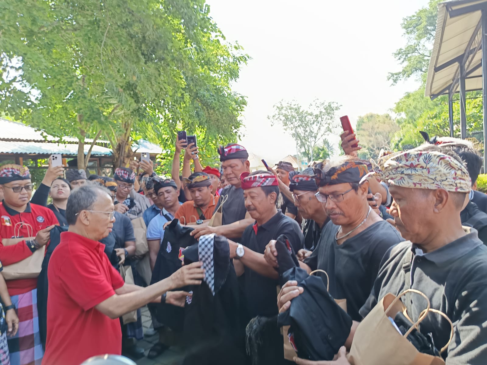 SERAHKAN BANTUAN: Gubernur Bali, Wayan Koster (baju merah) saat menyerahkan baji seragam kepada para pecalang. Ia menjanjikan insentif bagi pecalang sebesar Rp 50 juta per tahun.