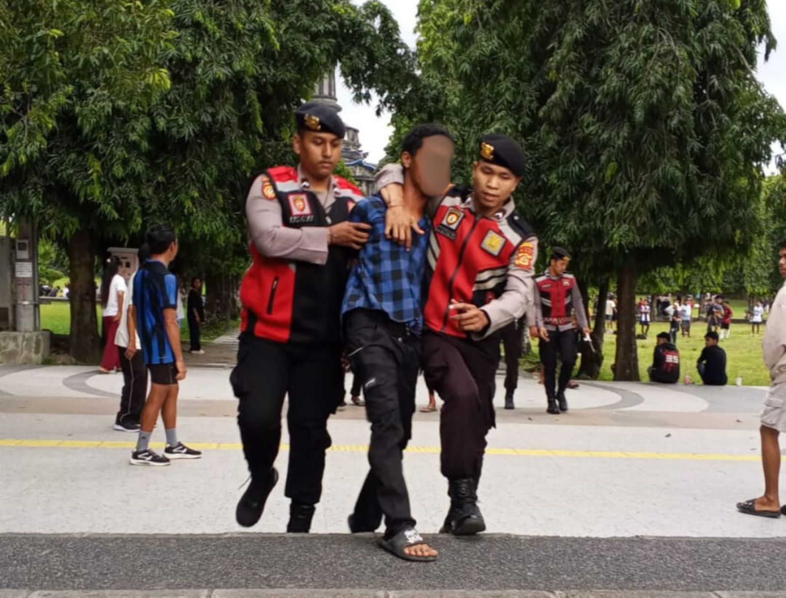 DIBAWA POLISI: Aparat kepolisian membawa seorang pria yang diduga menenggak minuman keras sambil membawa senjata tajam di Lapangan Renon.