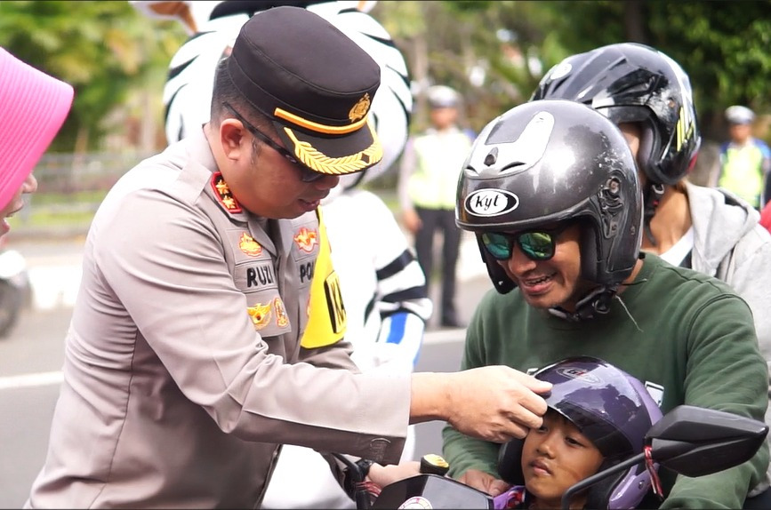 BAGIKAN HELM: Kapolres Buleleng, AKBP Ruzi Gusman (kiri) memberikan helm kepada anak pengguna jalan.