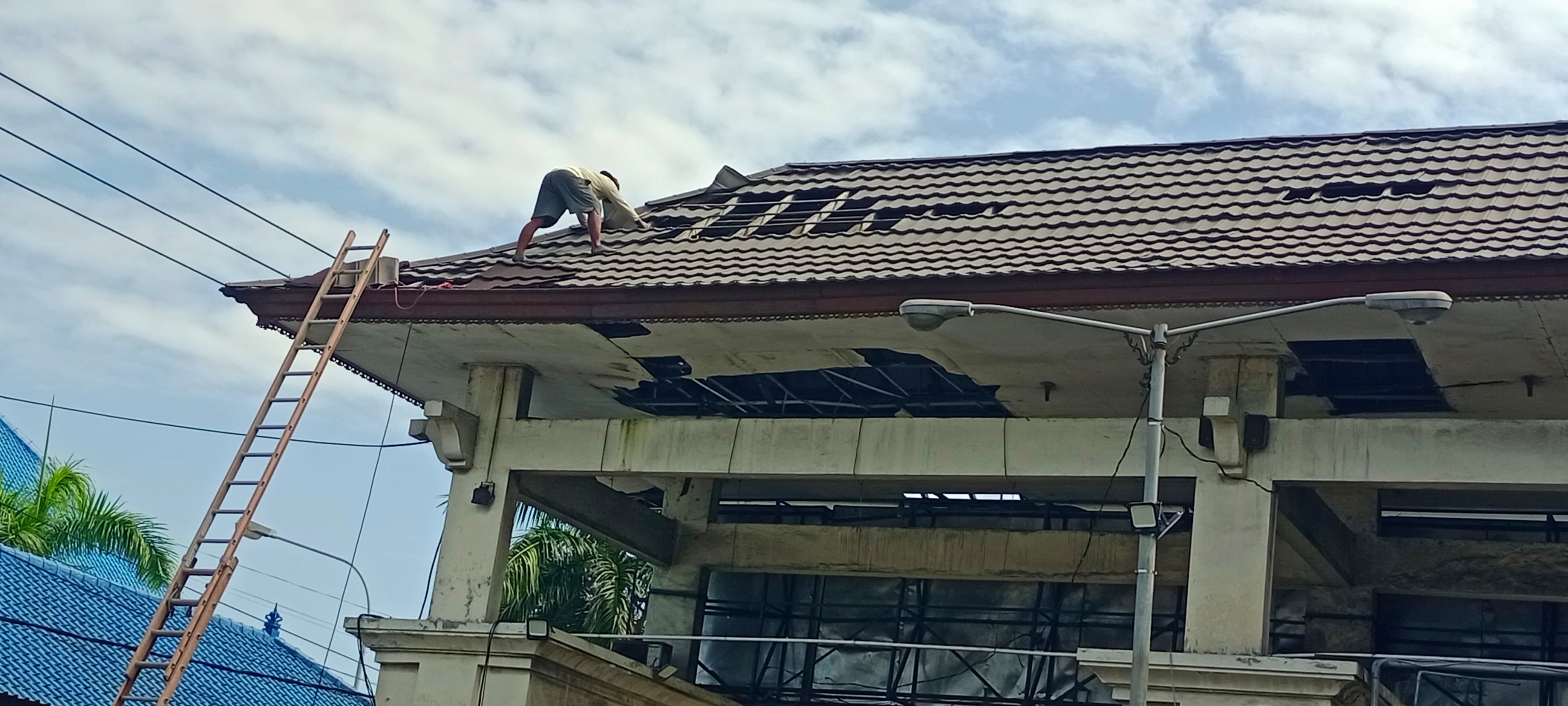PERBAIKI ATAP: Seorang pekerja nampak memperbaiki atap di dekat Terminal Gilimanuk.