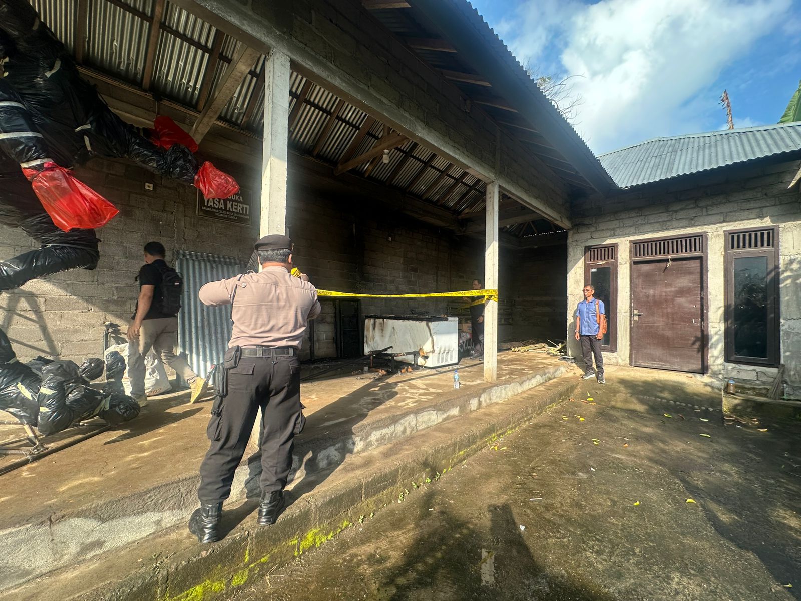 PASANG POLICE LINE: Aparat kepolisian memasang police line di balai suka duka Desa Bondalem, Kabupaten Buleleng, Bali. Sebuah ogoh-ogoh terbakar. Penyebabnya masih misterius.