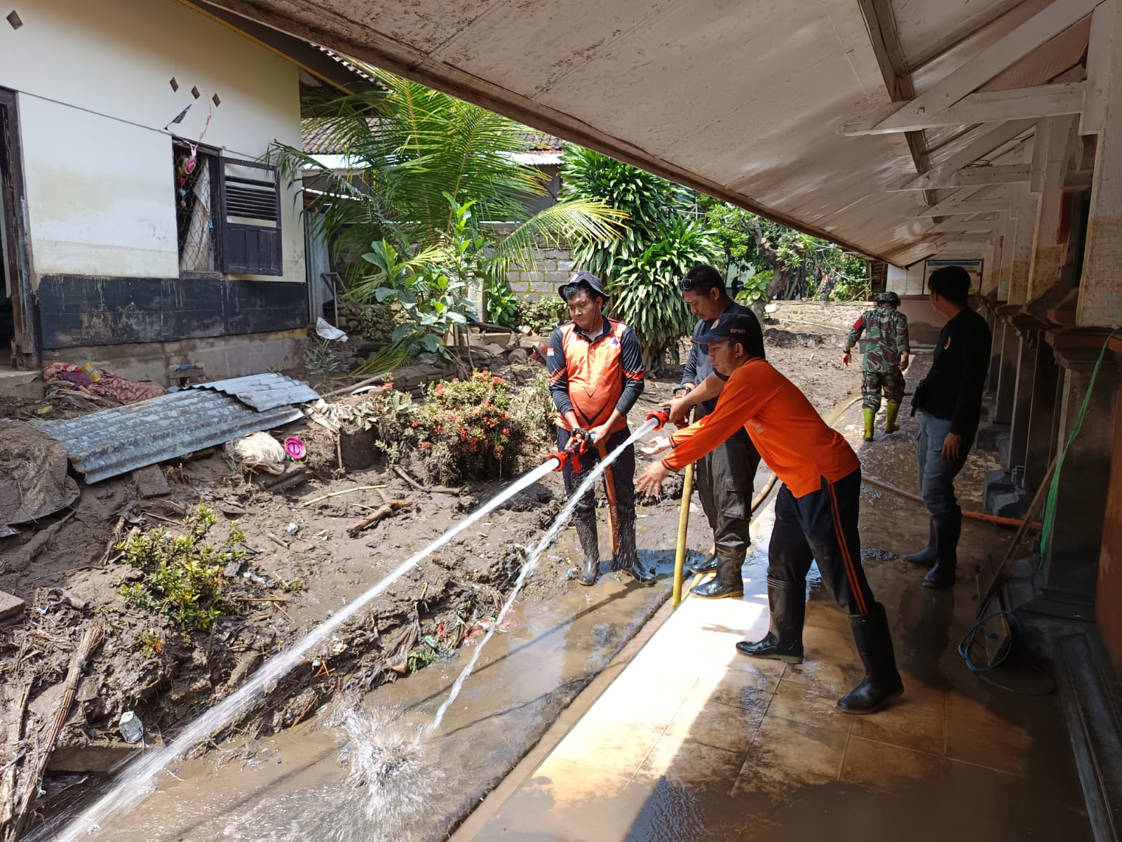TANGANI LUMPUR: Petugas BPBD Buleleng dan TNI masih berupaya membersihkan lumpur yang menutupi SDN 5 Banjar.