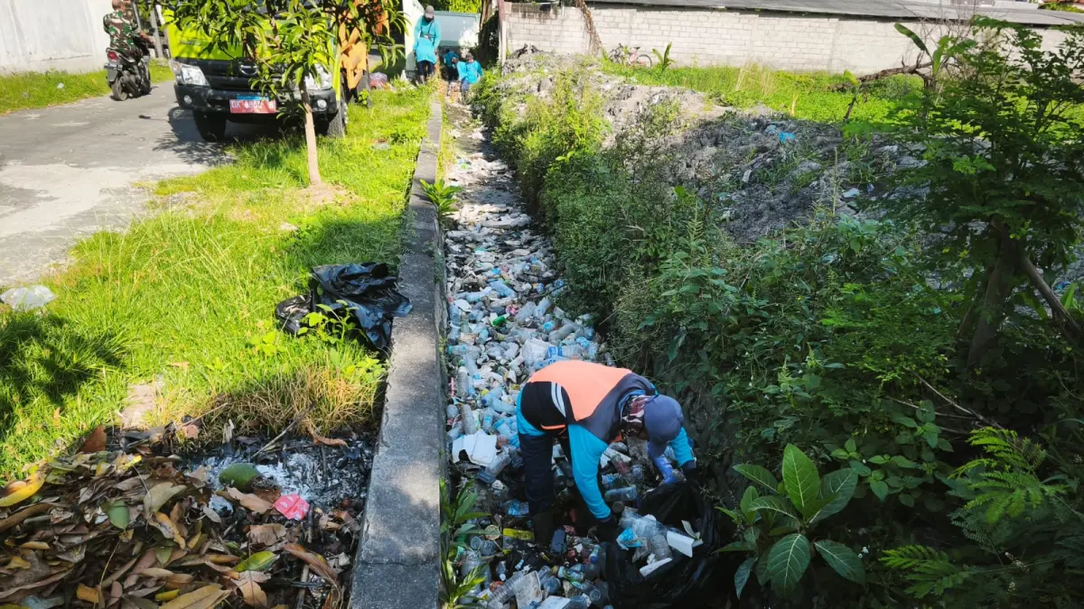 MENUMPUK: Petugas membersihkan sampah yang menumpuk di saluran air. Volume sampah meningkat, imbas pembatasan operasional TPA Suwung. (Pemkot Denpasar)