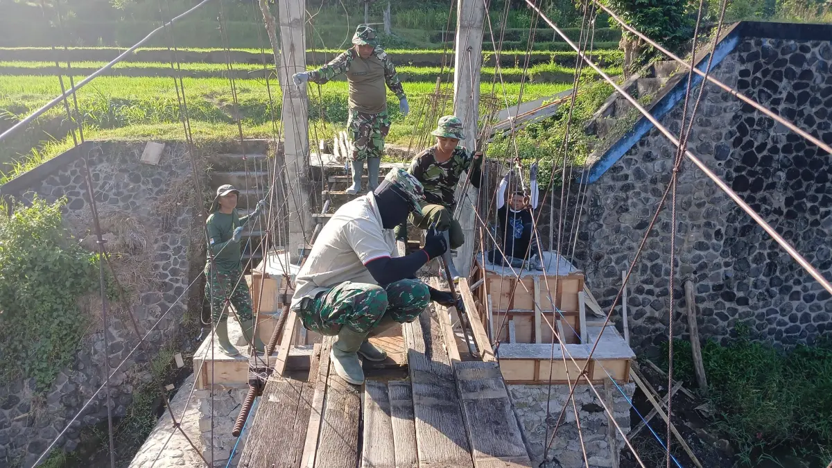 BUAT JEMBATAN: Personel TNI mengerjakan proyek jembatan yang membentang di Tukad Saba. Jembatan itu akan menjadi akses utama pelajar di Desa Lokapaksa menuju SDN 5 Ringdikit. (Kodim 1609/Buleleng)