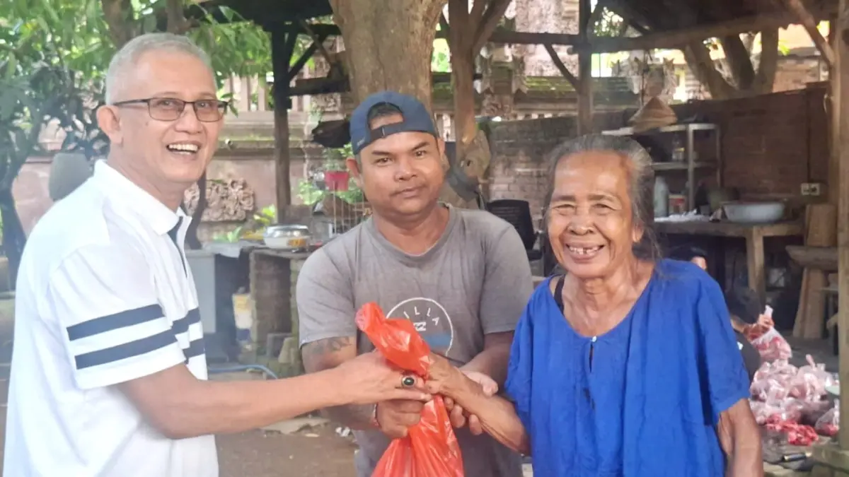 BAGIKAN DAGING: Ketua DPD II Golkar Buleleng, IGK Kresna Budi (kiri) membagikan daging babi gratis kepada lansia di Buleleng. (Francelino Junior/Radar Buleleng)