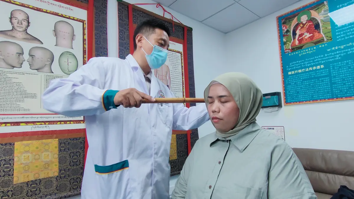TERAPI TRADISIONAL: Jurnalis asal Malaysia, Siti Zanariah Binti Nor Zin mencoba terapi tradisional ala Tibet di Nyingchi Tibetan Hospital, Tiongkok. (Eka Prasetya/Radar Buleleng)