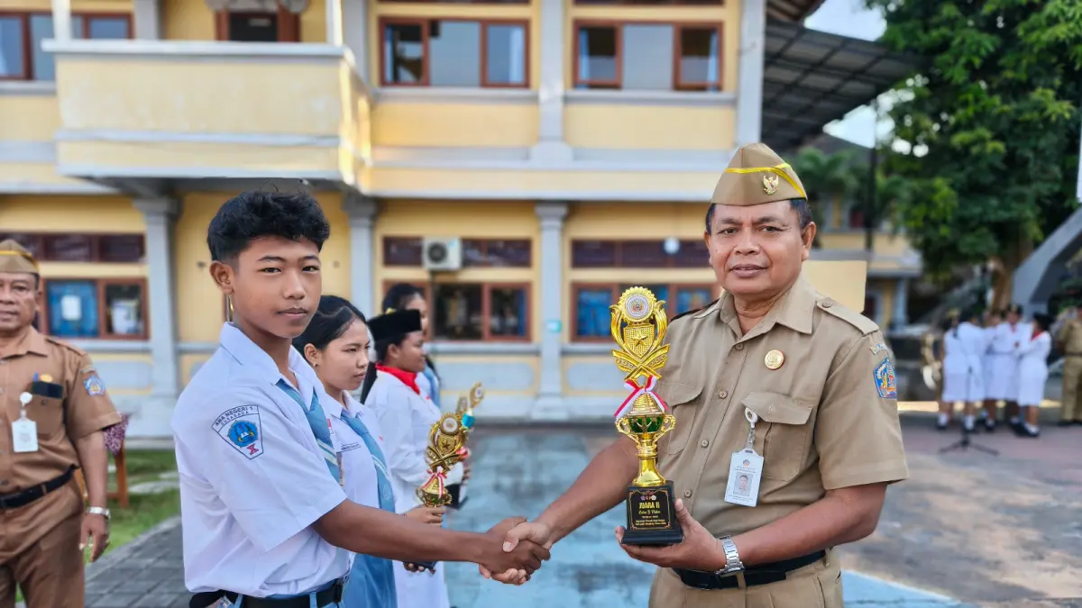 SERAHKAN PIALA: Kepala SMAN 1 Sukasada, Putu Suardana (kanan) menyerahkan piala kepada siswa berprestasi. (Pemkab Buleleng)