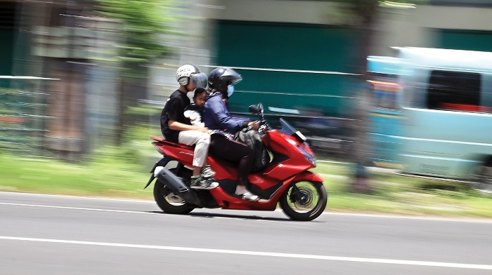 Pemudik membonceng anaknya melintas di Jalan Raya Nganjuk. Warga mulai mudik ke kampung halaman.