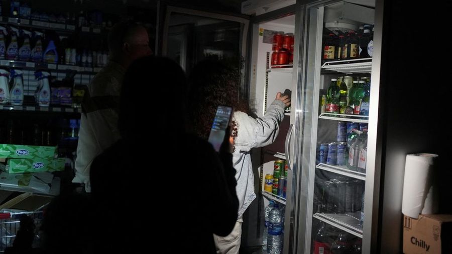 Warga menggunakan ponsel dan senter kepala untuk membeli bahan makanan di supermarket selama pemadaman listrik di Barcelona, ​​Spanyol.