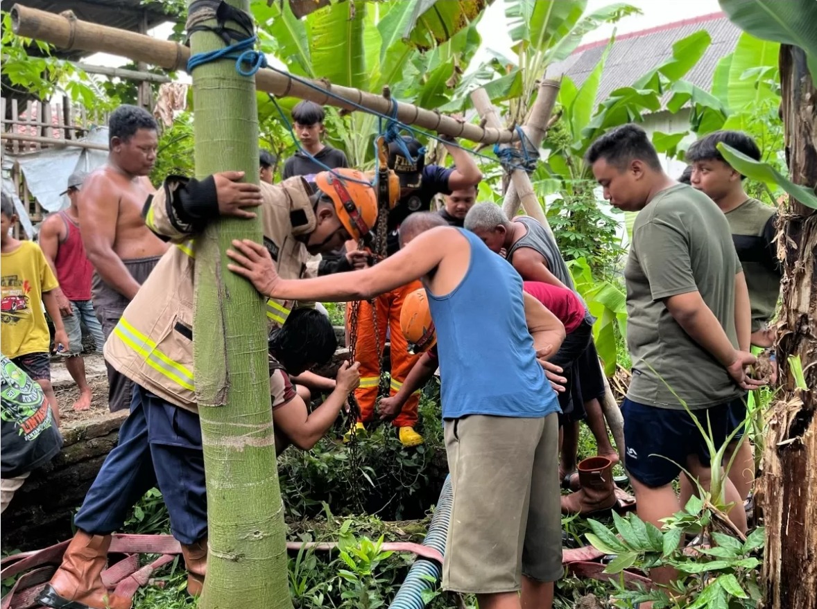 Petugas Damkarmat bersama warga sedang mengevakuasi ternak yang tercebur sumur