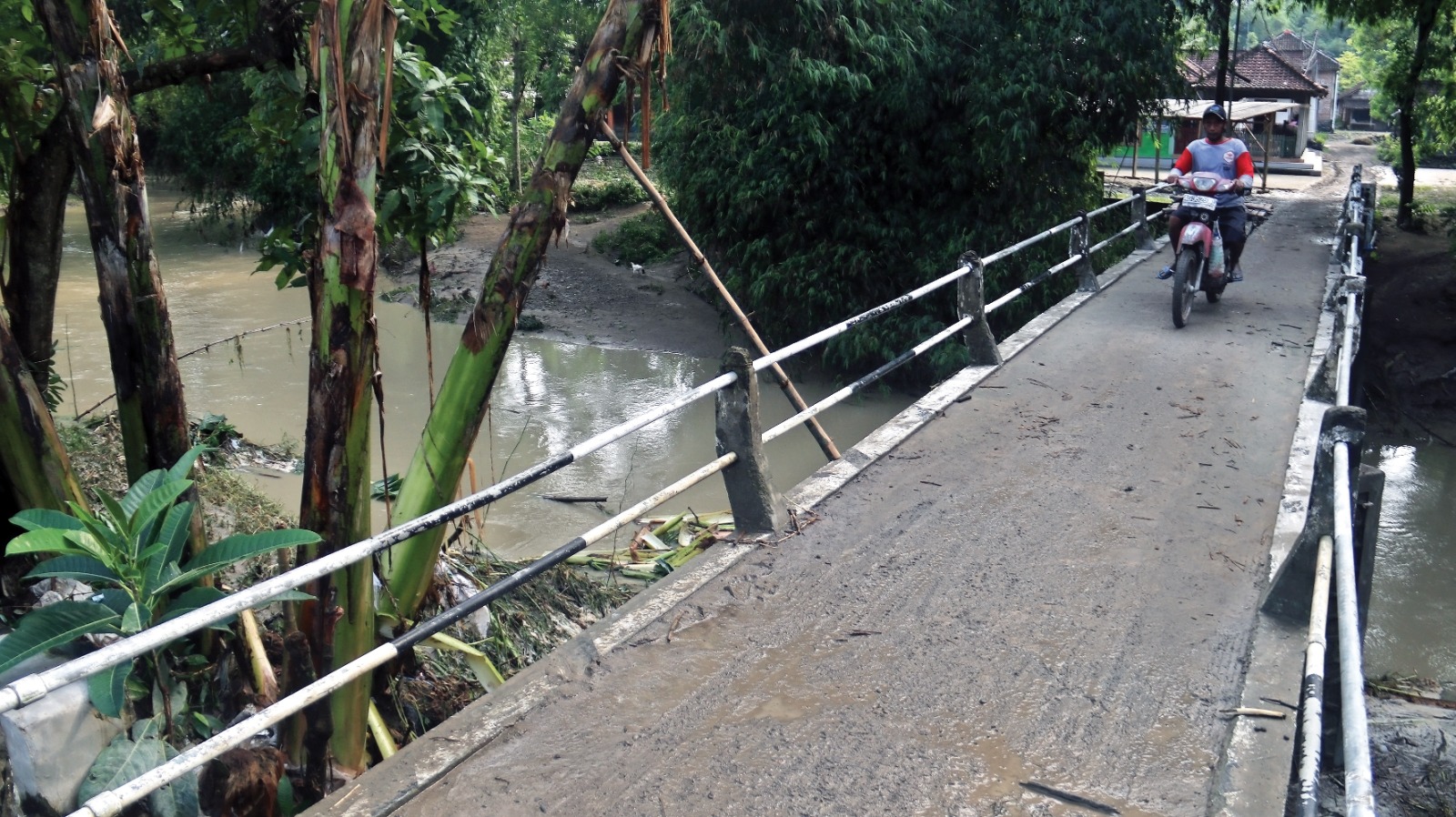 Warga Lengkong melintas di jembatan yang semoat tergenang air