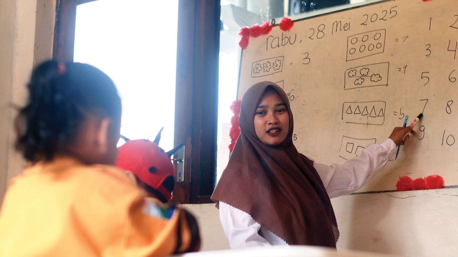 Guru TK Dharma Wanita mengajar berhitung pada anak didiknya di Balai Desa Kemlokolegi, Kecamatan Baron
