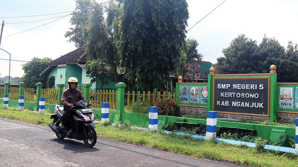 SEPI PEMINAT: Warga melintas di depan SMPN 5 Kertosono. Calon siswa baru yang mendaftar secara offline masih sembilan orang.