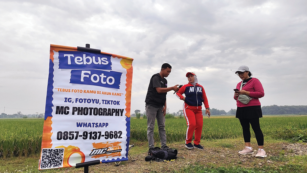 TAWARKAN FOTO: Gilang Ramadan menunjukkan hasil jepretannya ke warga. Satu foto dijual Rp 10 ribu.