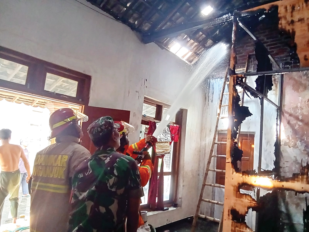 PADAMKAN API: Petugas Damkarmat Nganjuk menyemprot si jago merah yang melalap rumah Kholiq, warga Desa Jetis kemarin.