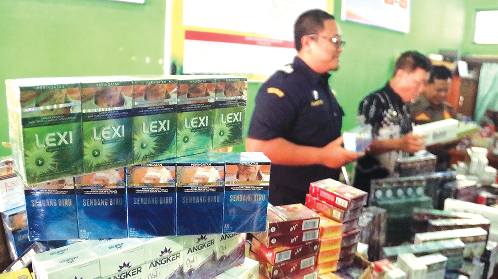 MERUGIKAN NEGARA: Kasatpol PP Suharono menunjukkan rokok ilegal yang berhasil disita kemarin.