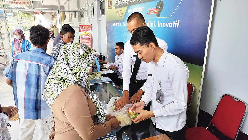 CEK MAKANAN: Pembesuk menunjukkan makanan kepada petugas Rutan Nganjuk sebelum dibawa masuk.