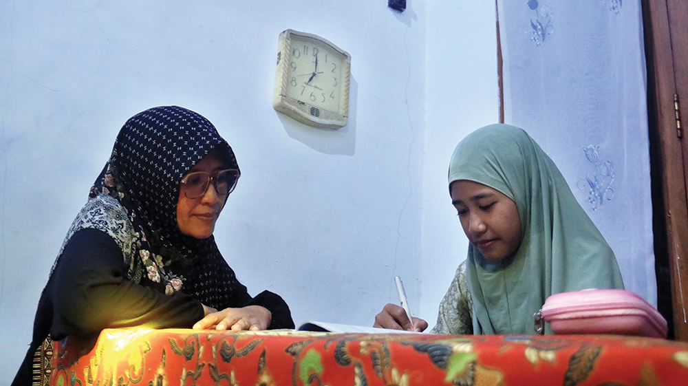JAM 7 MALAM: Mahrunia Elok Nur Sabrina, siswi SDN 4 Kapas belajar saat Jam Malam ditemani ibunya tadi malam. DIsdik minta orang tua harus mengawasi anakn