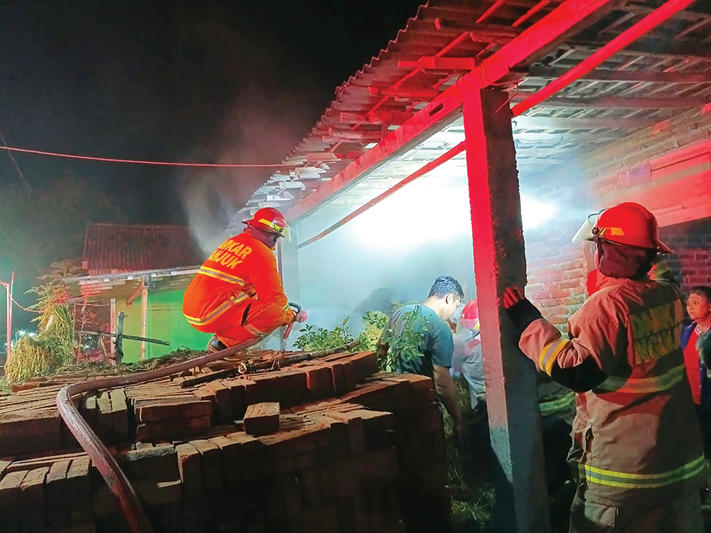 BERKOBAR: Petugas Damkarmat Nganjuk memadamkan si jago merah di Kelurahan Werungotok, Nganjuk. Kemarin pagi mereka mengevakuasi ular piton.