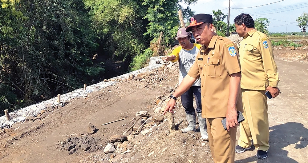 Kepala Pelaksana (Kalaksa) Badan Penanggulangan Bencana Daerah (BPBD) Nganjuk Sutomo mengecek jalan ambles di Desa Jintel, Rejoso.