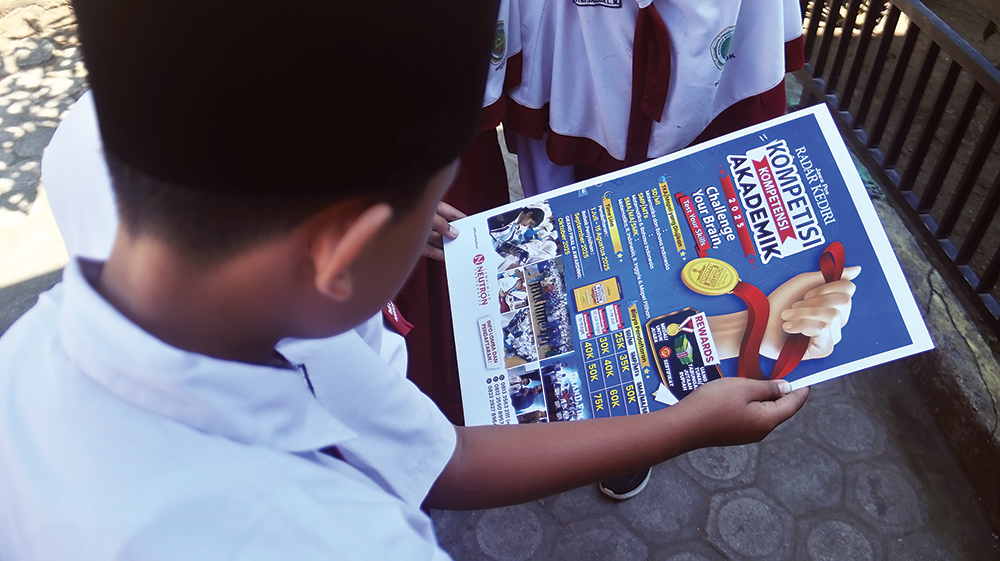 ANTUSIAS: Siswa MIN 2 Nganjuk melihat pamflet Kompetisi Kompetensi Akademik yang digelar Jawa Pos Radar Kediri. Mereka bertekad mempertahankan prestasi jadi juara tahun lalu.