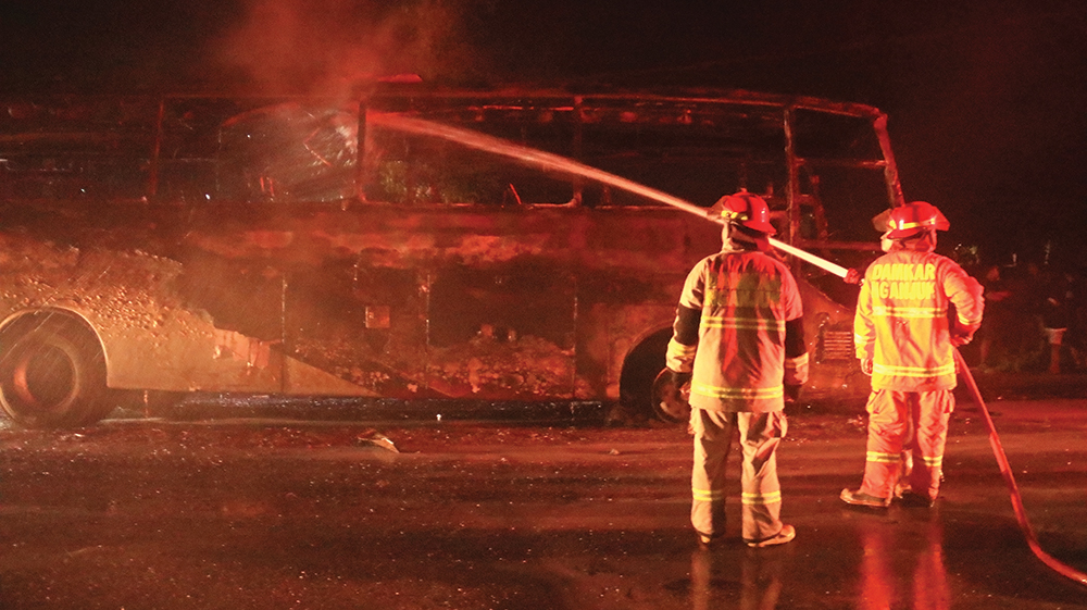 TINGGAL KERANGKA: Petugas Damkarmat Nganjuk menyemprot Neo Harapan yang terbakar setelah bertabrakan dengan sepeda motor Honda Beat di Jalan Raya Kertosono-Nganjuk, Desa Nglundo, Sukom
