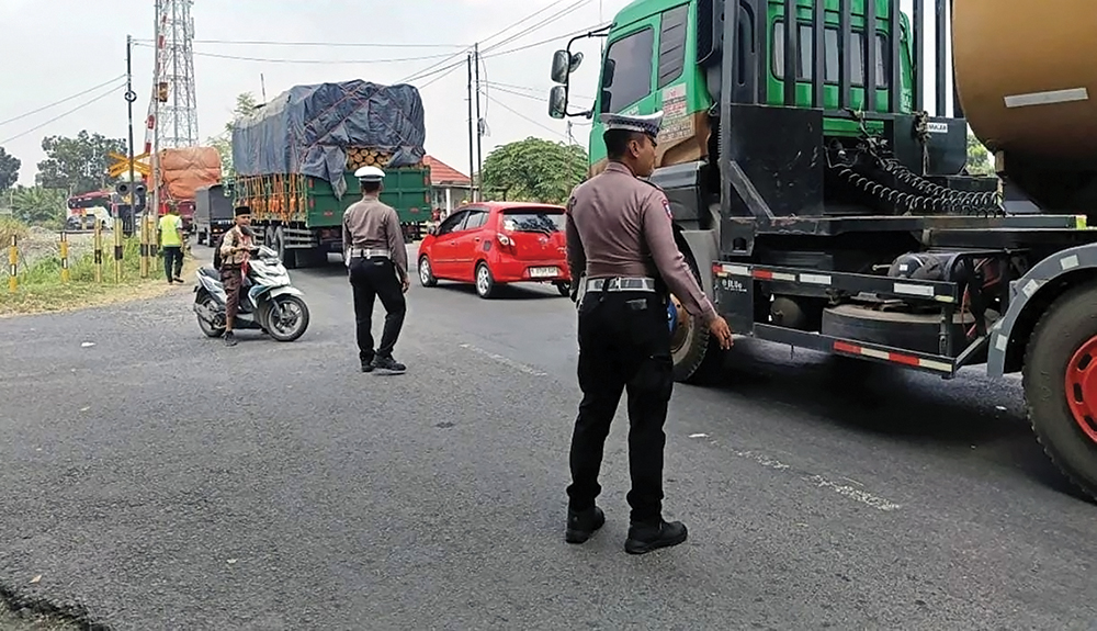 RAWAN LAKA: Petugas mengatur arus lalu lintas di dekat perlintasan KA di Baron. Lokasi itu masuk blackspot.