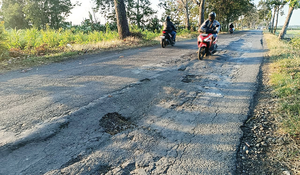 BERBAHAYA: Pengendara sepeda motor meiintas di Jalan Raya Sukomoro-Pace yang bergelombang dan berlubang kemarin. Kondisi jalan yang rusak membuat pengendara sepeda motor oleng