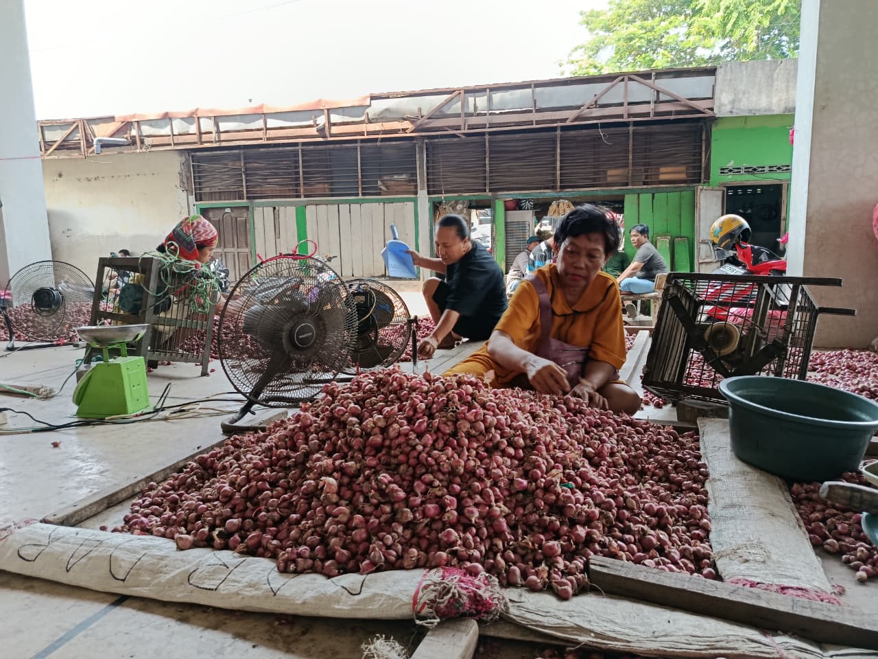 Salah satu pedagang di Pasar Sukomoro sedang mengeringkan bawang merah jualannya