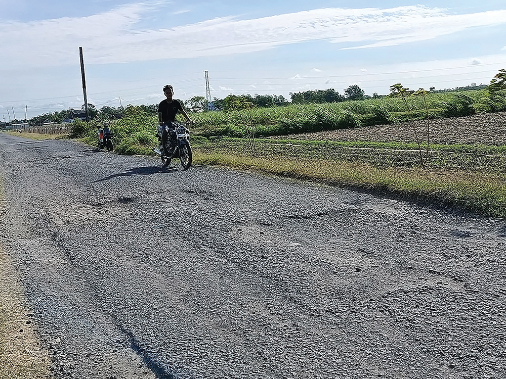 BERBAHAYA: Pengendara sepeda motor sedang melintas di jalan rusak yang berada di Desa Pacewetan, Kecamatan Pace kemarin. Jalan tersebut banyak lubang.