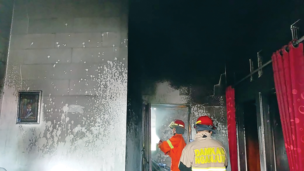 HANGUS: Petugas Damkarmat Kabupaten Nganjuk berusaha memdamkan api yang melalap dapur rumah warga Loceret yang dilalap si jago merah.