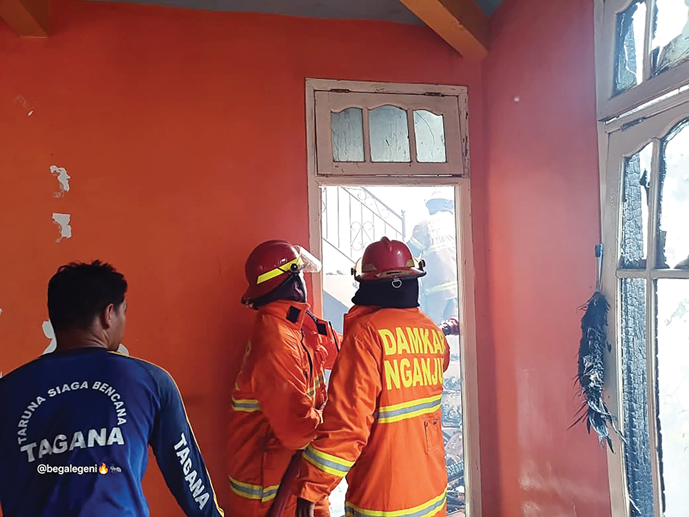 MEMBARA: Petugas Damkarmat Kabupaten Nganjuk berusaha memadamkan si jago merah yang melalap rumah warga Desa Mojoduwur, Kecamatan Ngetos.