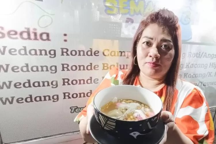 Seorang penjual menunjukkan semangkuk wedang ronde hangat yang siap dinikmati.