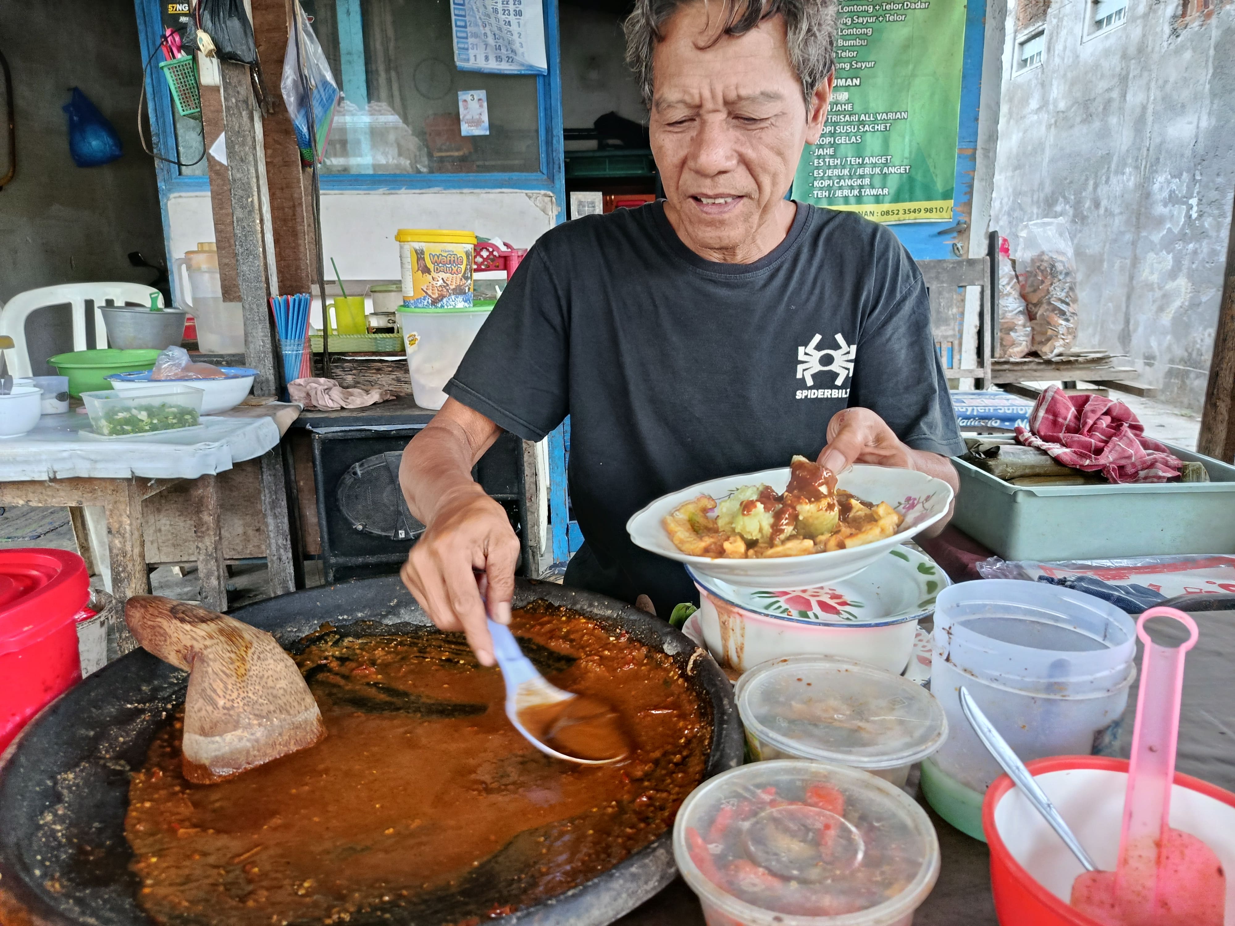Pak Saifu sedang membuatkan pelanggan tahu telor lontong