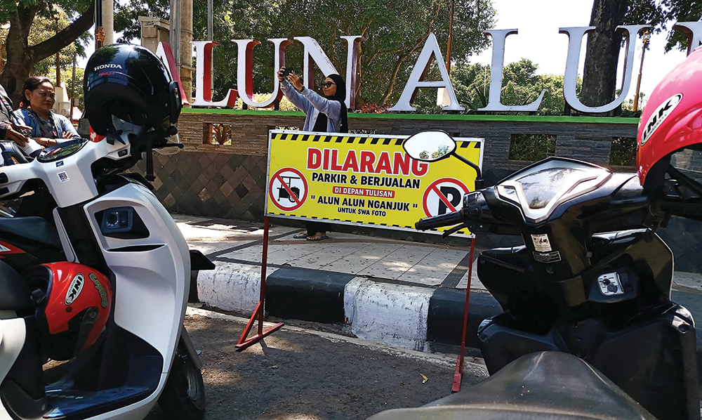 MASIH NGEYEL: Pengunjung Alun-Alun Nganjuk memarkir kendaraannya di depan papan larangan parkir dan berjualan kemarin. Papan Nama
