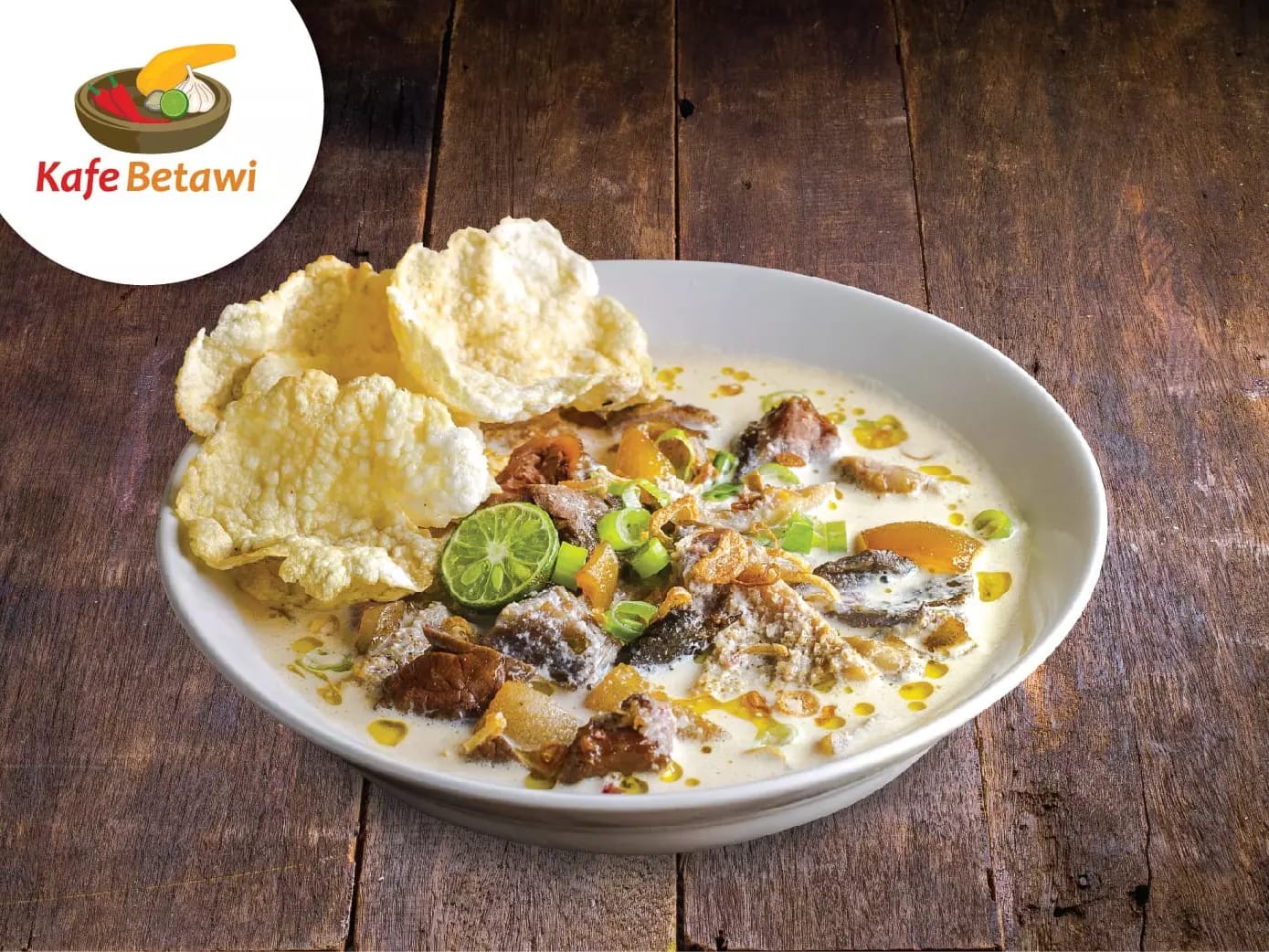 Semangkuk Soto Daging Betawi dengan kuah santan gurih tersaji lengkap dengan kerupuk dan jeruk limau.