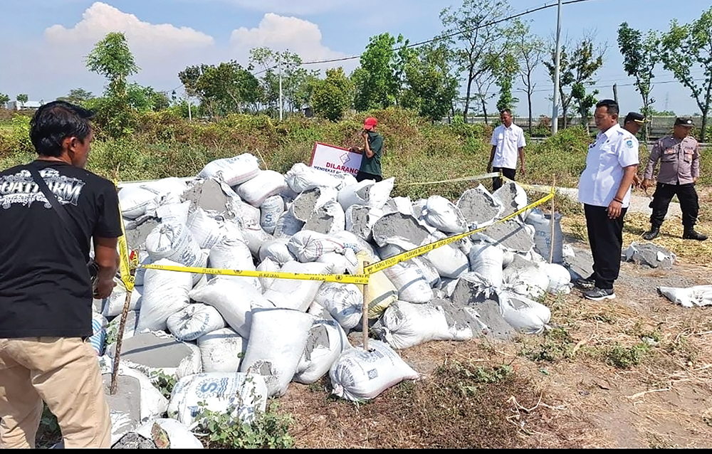 CARI PEMBUANG LIMBAH: Petugas memasang police line ditumpukan limbah berbahaya yang dibuang di tepi jalan Desa Kemlokolegi, Kecamatan Baron kemarin.