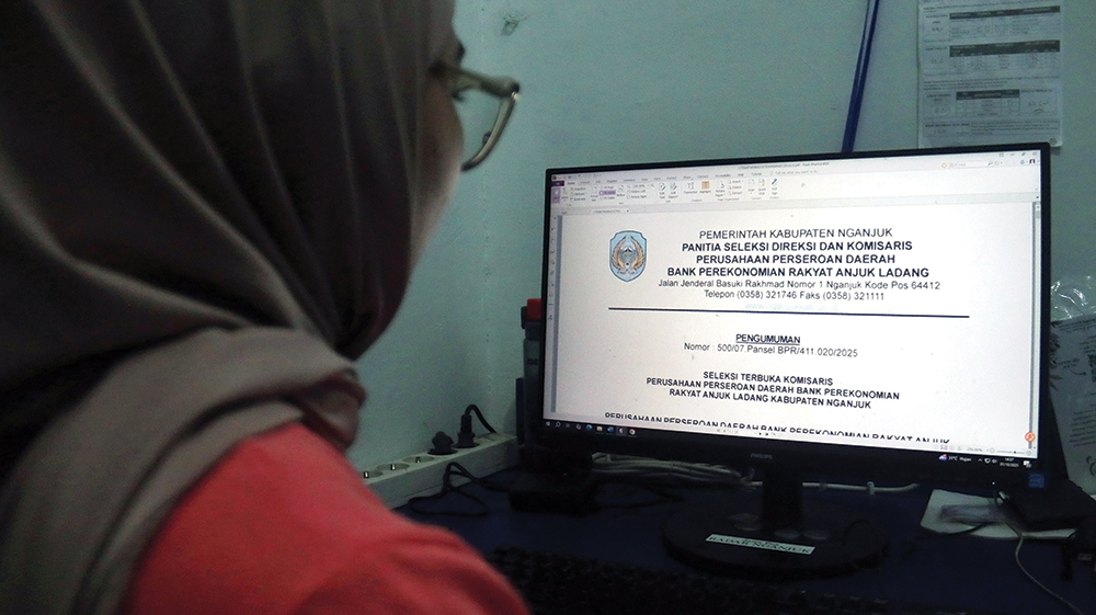 SEPI PEMINAT: Warga melihat pengumuman seleksi terbuka jabatan komisaris BPR Anjuk Ladang kemarin.